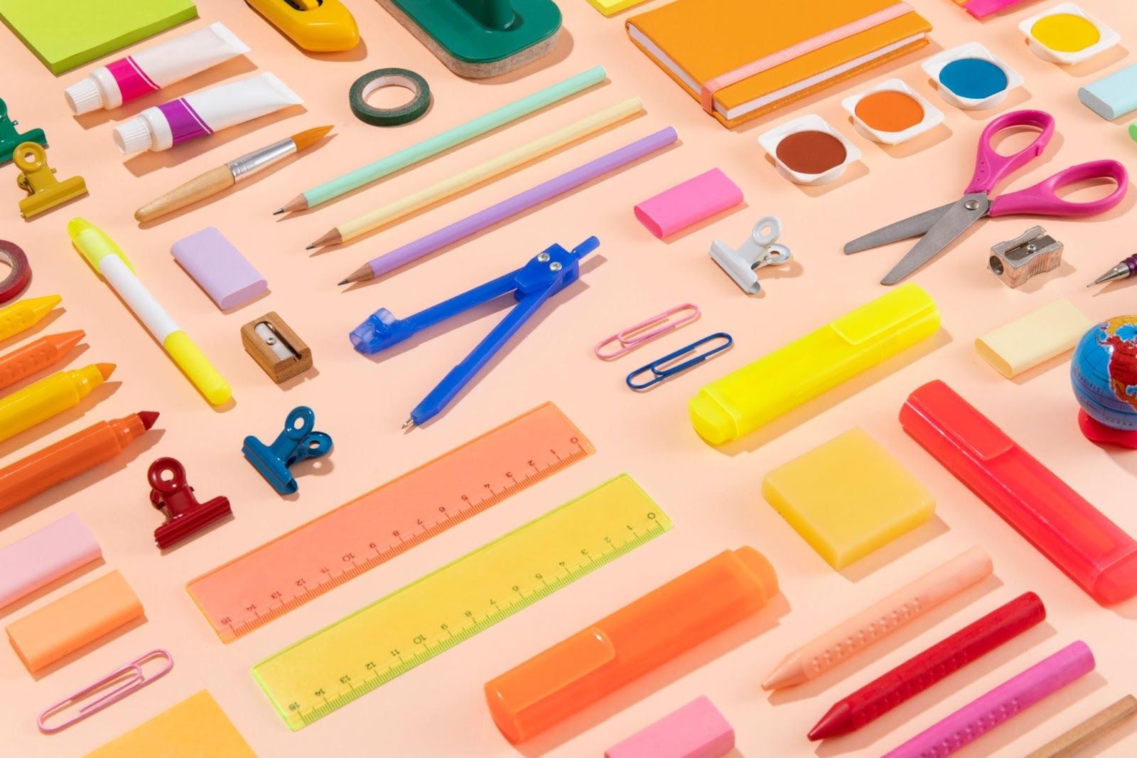 A variety of school supplies arranged on a pink background.