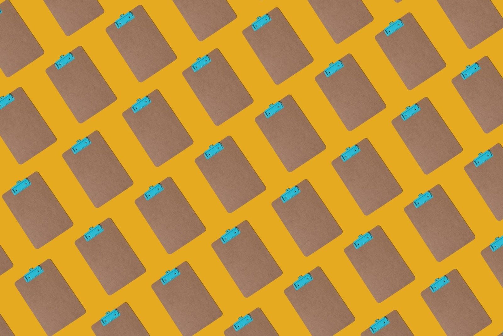 Pattern of cardboard clipboard with turquoise metal clip on yellow background.